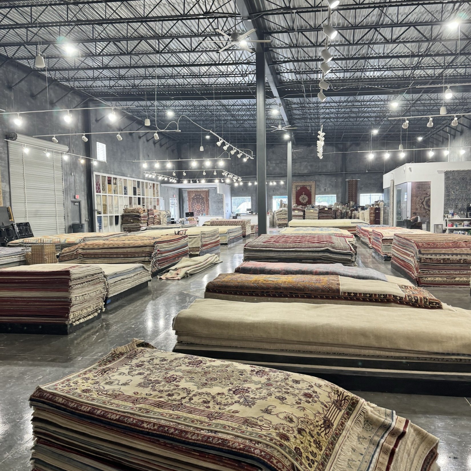 Inside the Arteverk Houston showroom — rows of one-of-a-kind hand-knotted rugs laid out in the gallery