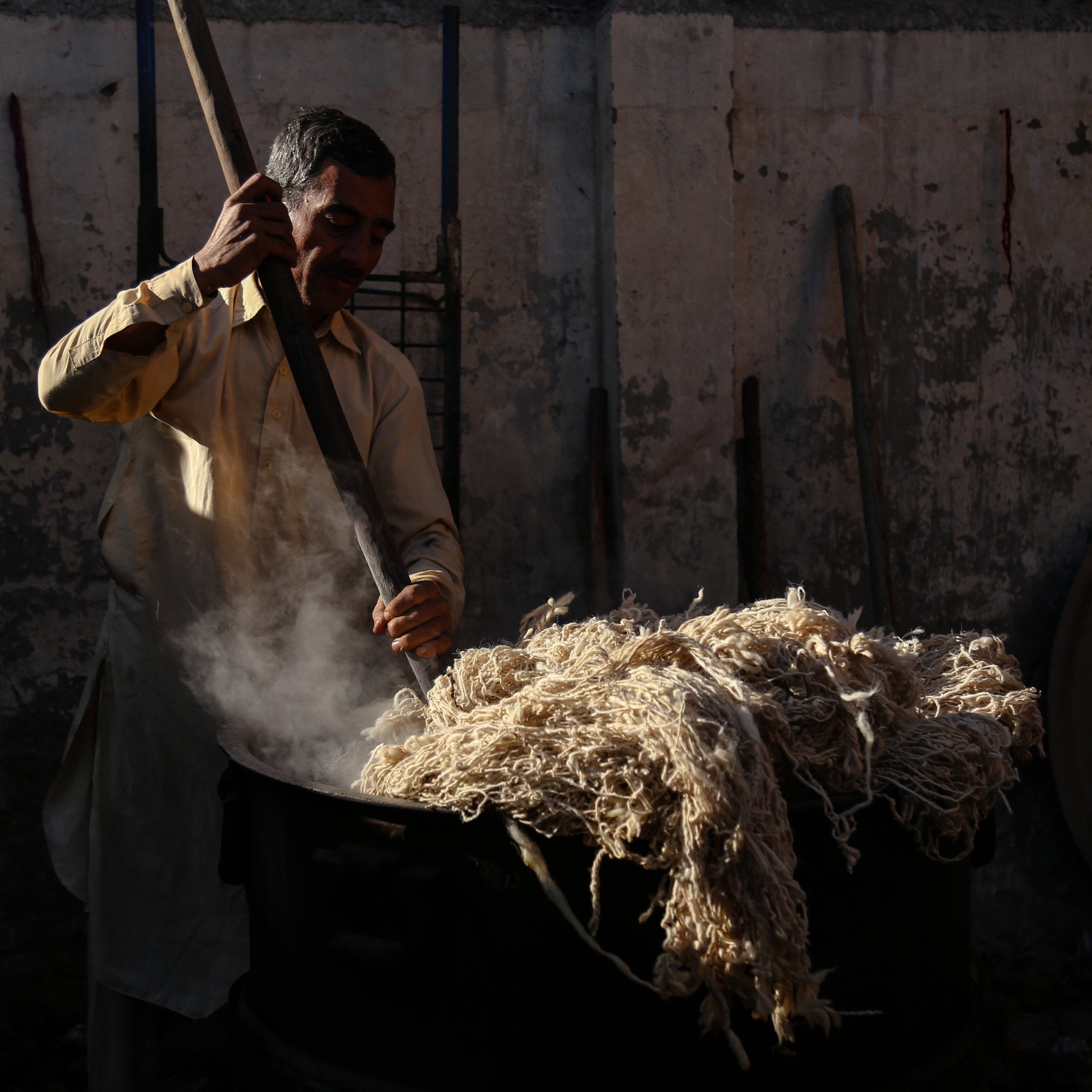 An artisan stirring wool in a steaming vat of natural vegetable dye