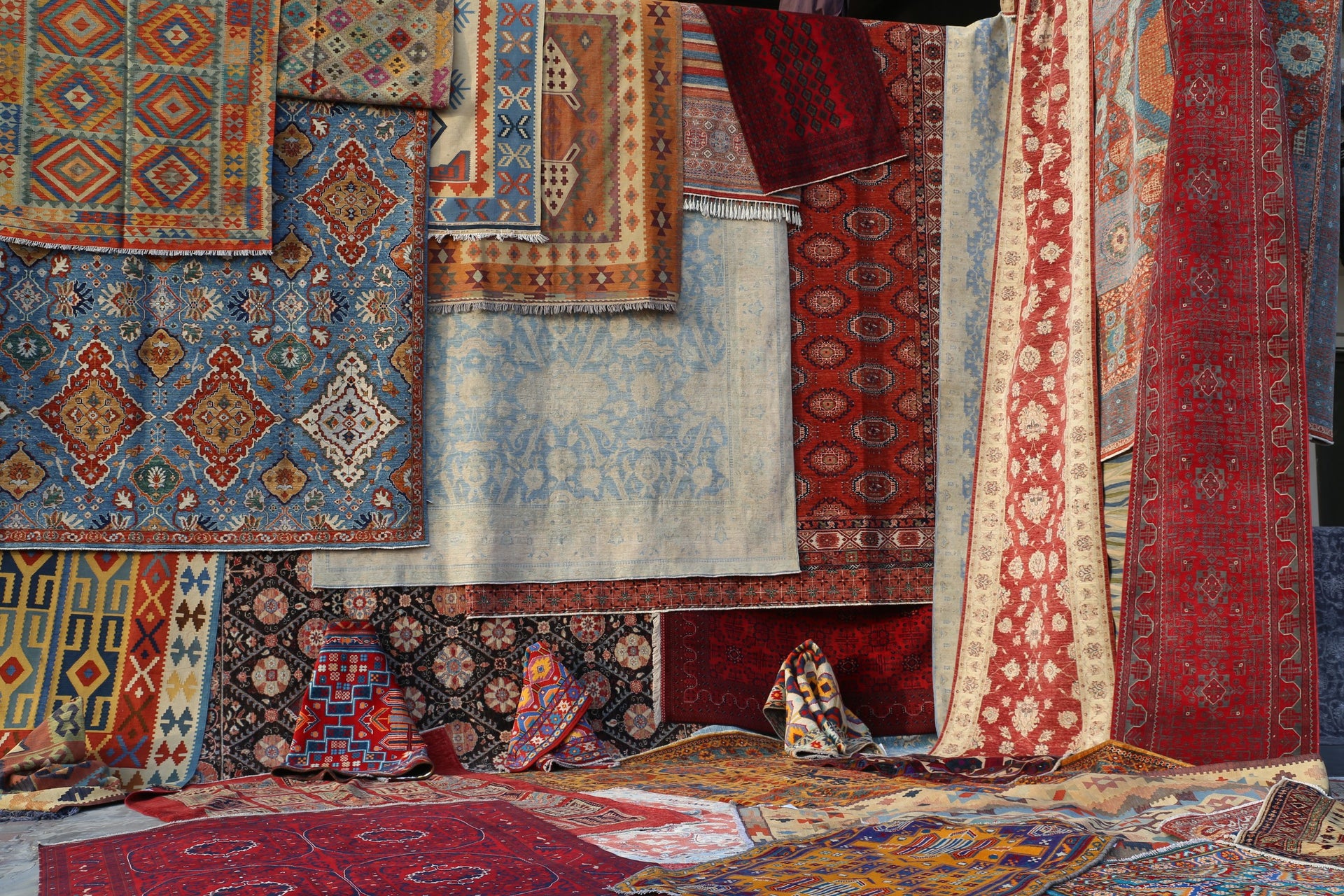A gallery wall of one-of-a-kind hand-knotted rugs in rich blues and reds at Arteverk in Houston