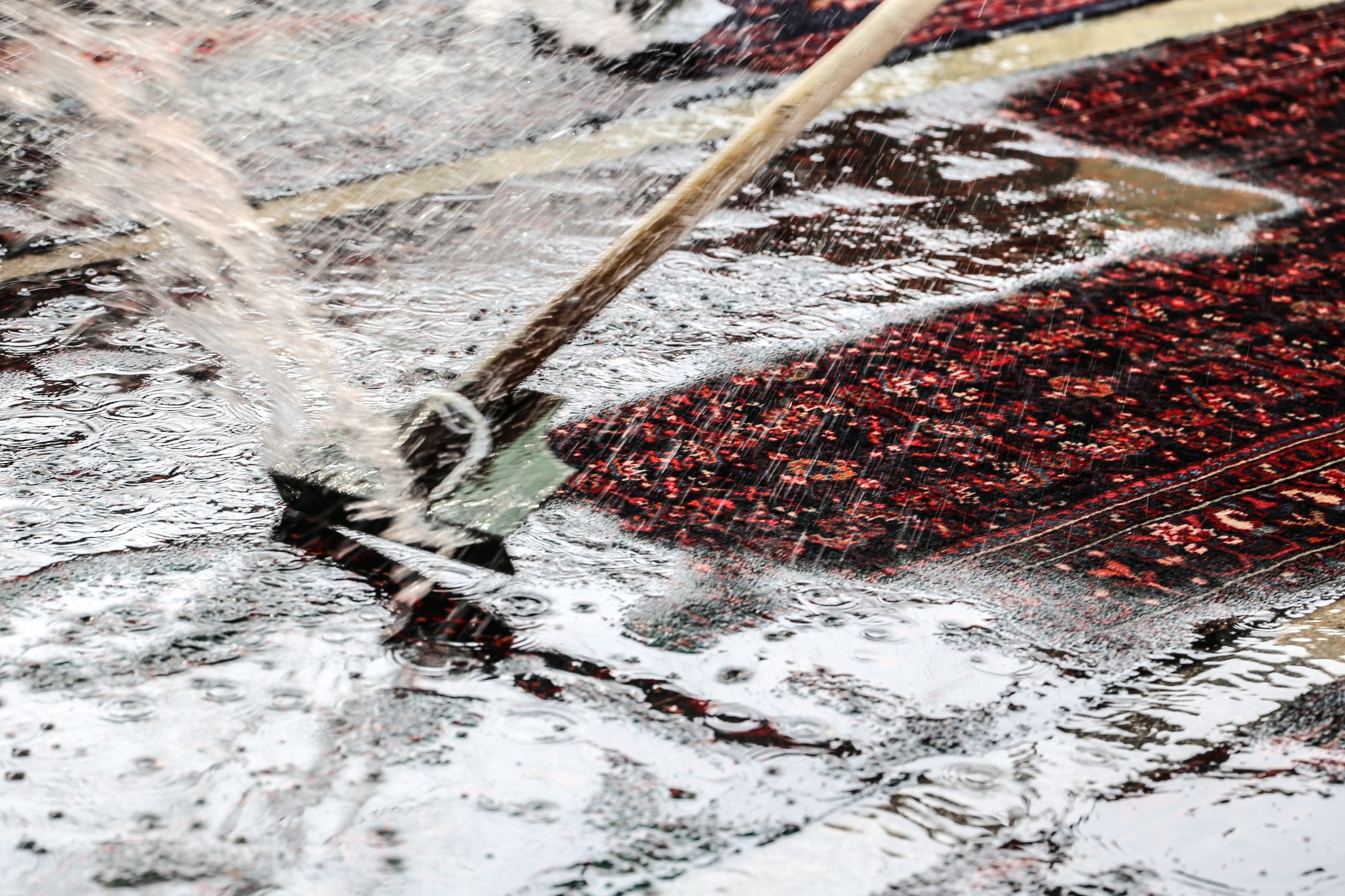 A hand-knotted rug being washed and cleaned by hand during restoration at Arteverk in Houston